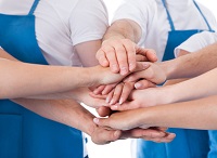 Group of cleaners stacking hands